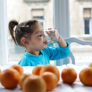 Kind trinkt aus Wasserglas.