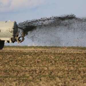 Ein landwirtschaftliches Fahrzeug düngt ein Feld, was zur Belastung des Grundwassers mit Nitrat führen kann.