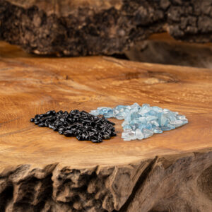 Eine Komposition aus glänzenden, schwarzen Obsidian- und hellblauen Aquamarin-Kristallsteinen, arrangiert auf einer rustikalen Holzoberfläche.