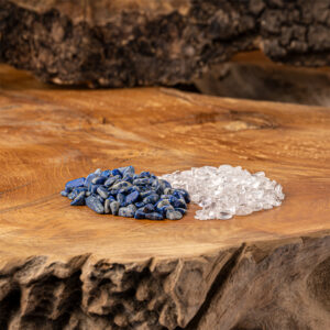 Eine Mischung aus blauen Lapislazuli- und klaren Bergkristall-Edelsteinen, sorgfältig arrangiert auf einer rustikalen Holzoberfläche.