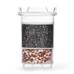 Eine transparente Wasserfilter-Kartusche, die im oberen Bereich mit Aktivkohle und im unteren Bereich mit Mineralkugeln gefüllt ist.